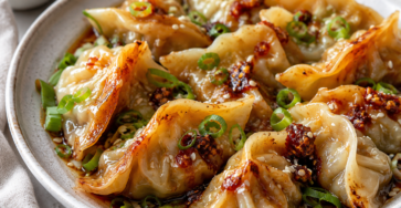 One Pan Baked Dumplings served with sesame seeds, green onions, chili crisp, and fresh herbs